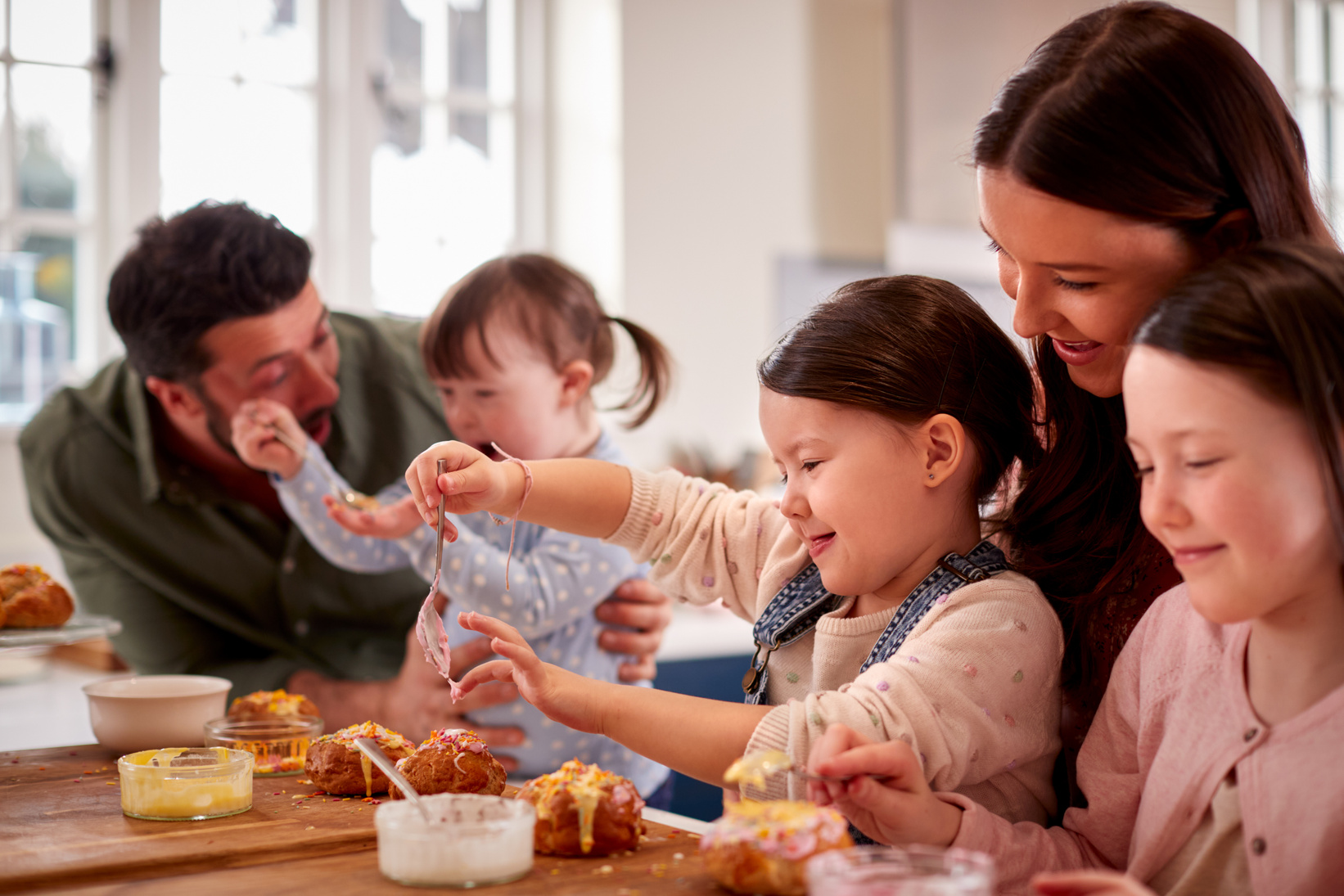 with down Syndrome Daughter Baking and Decorating Cakes Sitting around Table at Home